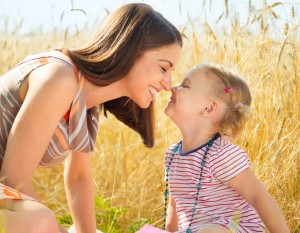 Happy young mother with little daughter on field in summer day