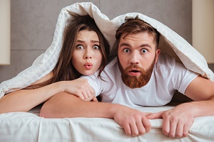 couple in bed looking surprised