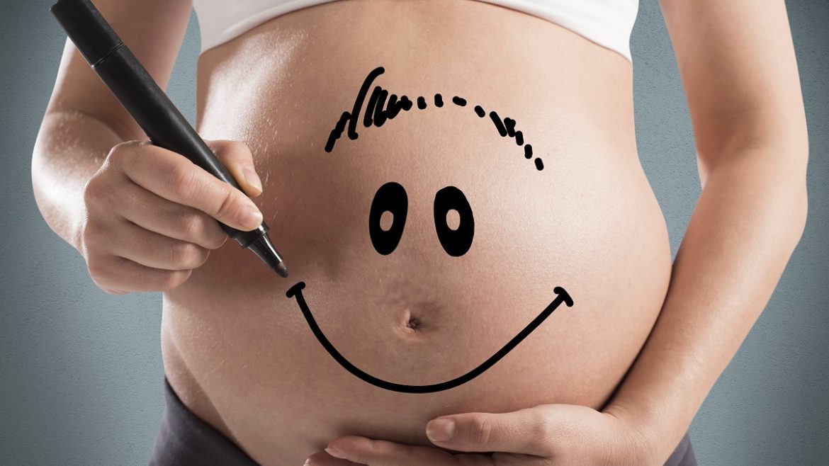 pregnant woman with smiley face on belly
