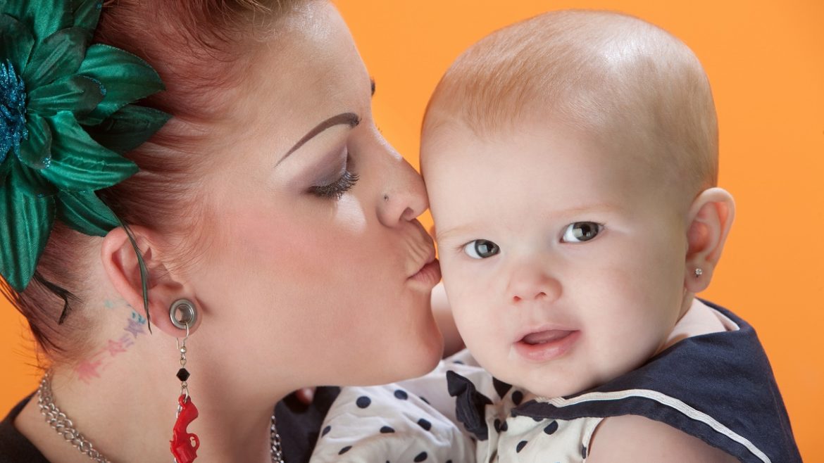 tattooed woman kissing baby