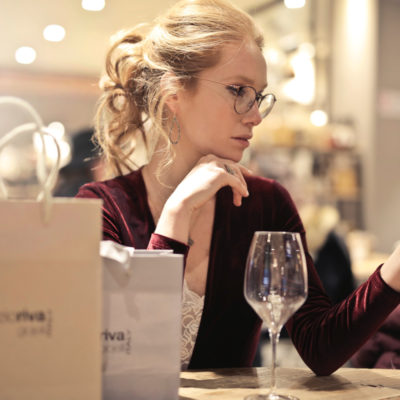 Woman with glasses, shopping, glass of wine, looking at phone