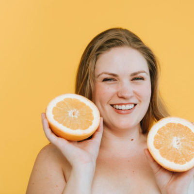 Woman naked from shoulders up holding grapefruit halves