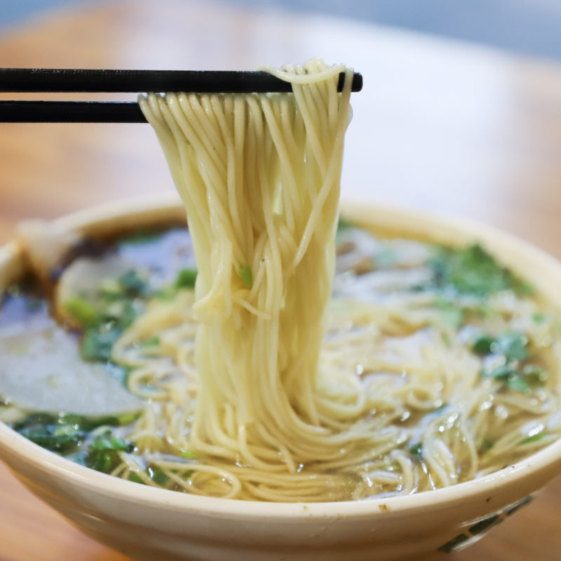 Ramen noodle bowl with chopsticks holding some noodles