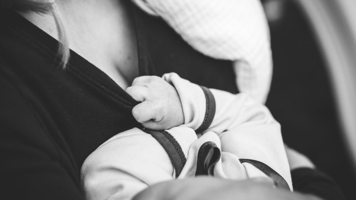 Close up of woman holding newborn baby near chest