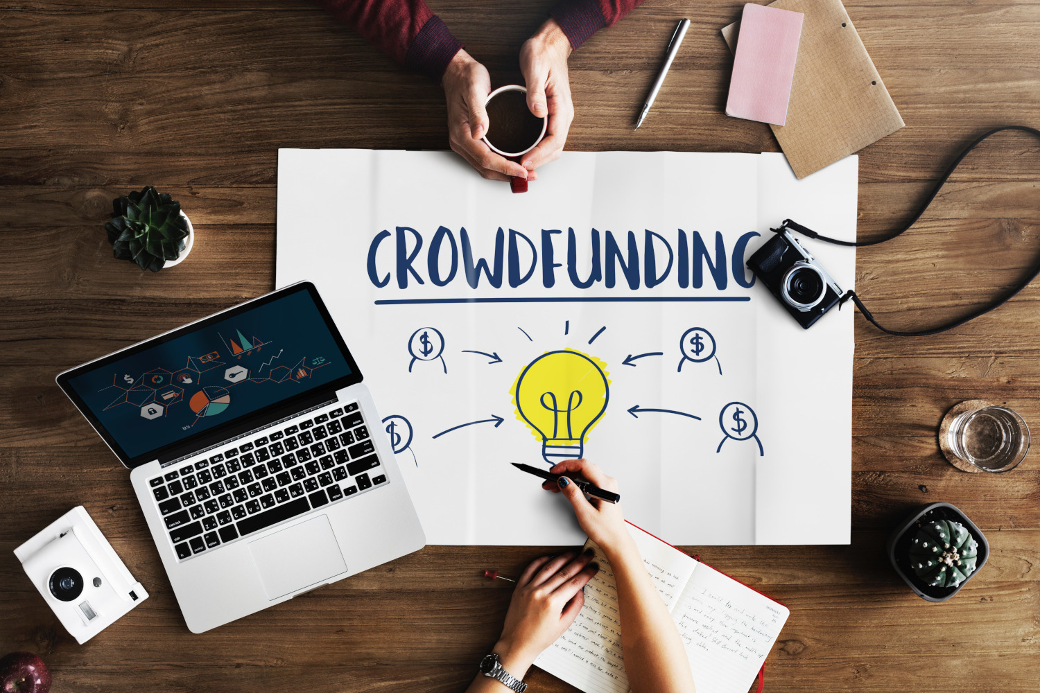 Crowdfunding sign on a desk with two people planning.