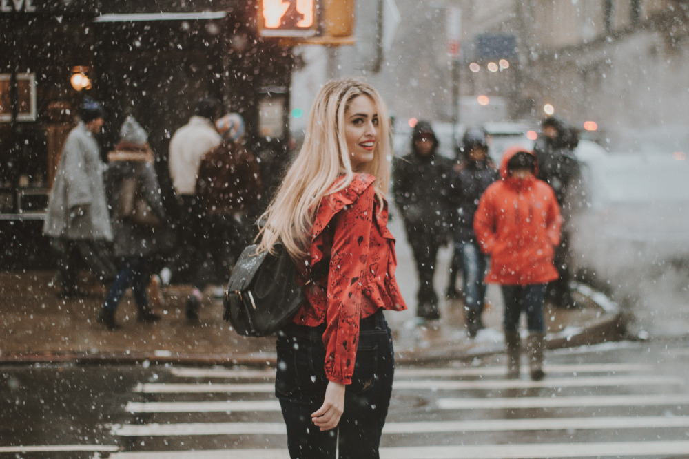 Woman walking on the street while it's snowing.