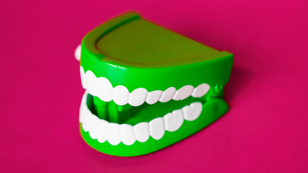 Green wind up chattering teeth with plain, hot pink background.