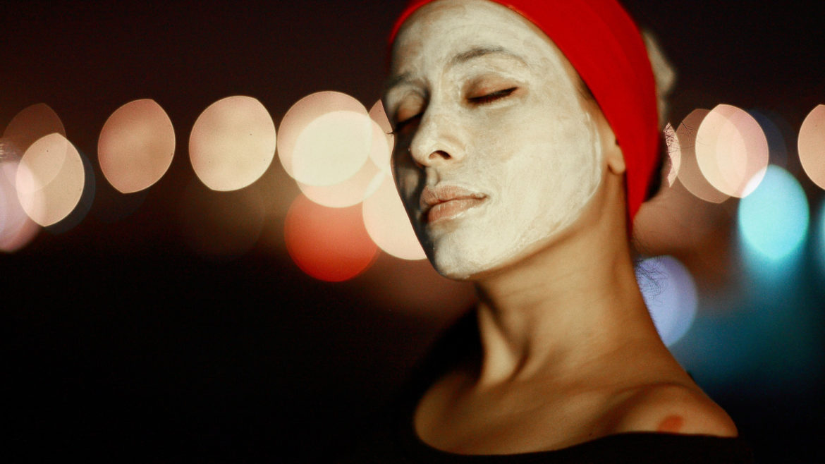 Woman with a face mask on wearing a red headband with her hair pulled up.