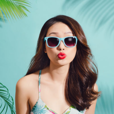 Summer fashion portrait of beautiful woman posing in summer outfit blowing a kiss.