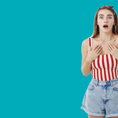 Woman and red and white striped bodysuit and jean shorts hearing shocking news.